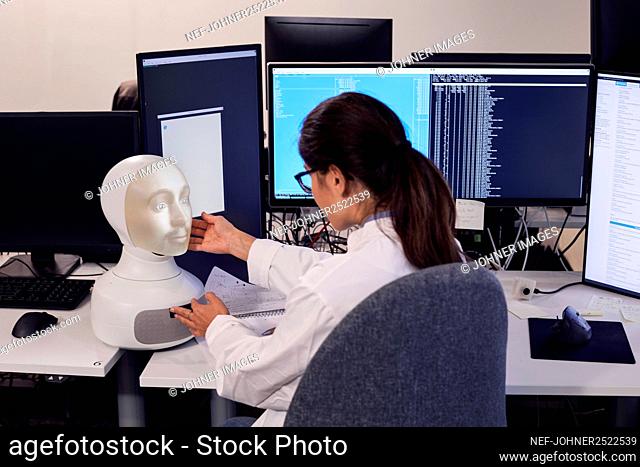 Female engineer building robot with human face