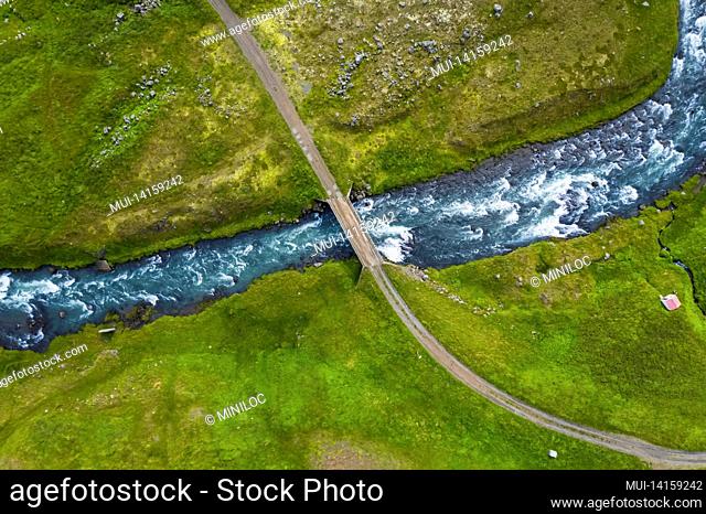 iceland. aerial view of road and small bridge over blue mountain river. aerial scenic view of iceland landscape. travel vacation concept