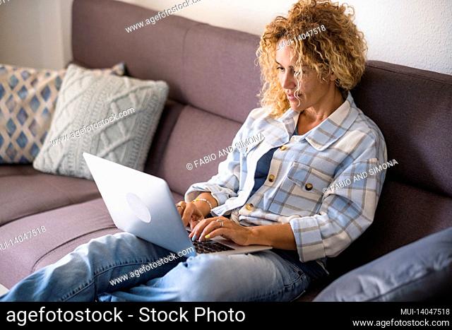 adult pretty female people watch internet computer contents lay down and relaxing on the couch at home - woman smile looking display and enjoy alternative job...