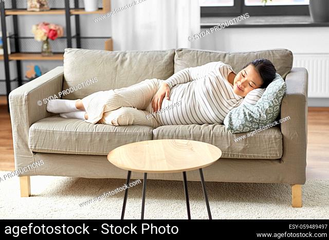 pregnant asian woman sleeping on sofa at home