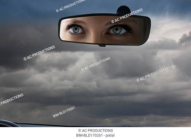 Eyes of Caucasian woman reflecting in rear view mirror
