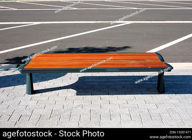 A resting bench made of wood on a parking lot