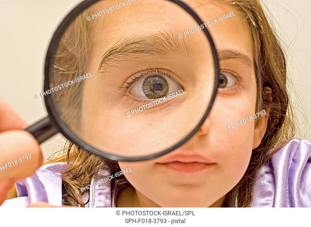 Young girl of 7 playing with a magnifying glass