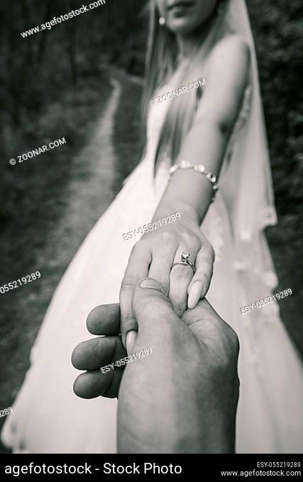 Close-up of wedding details. Groom's hand holding bride's hand. The bride's wedding ring on the finger. Wedding day