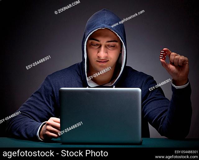 Young man wearing a hoodie sitting in front of a laptop computer gambling