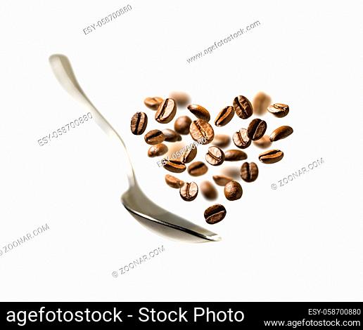 Coffee beans in the shape of a heart and a spoon in flight