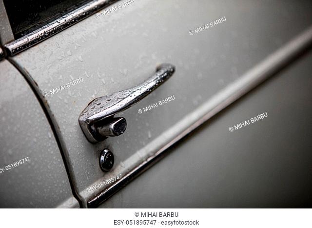 Close up shot of a vintage car door handle with rain drops