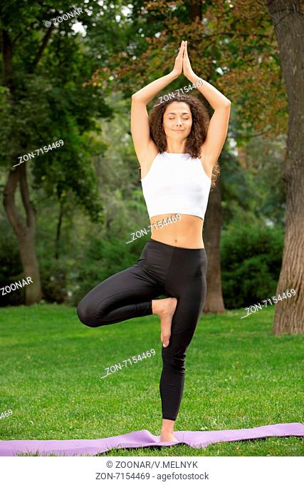 Smiling pretty woman doing yoga exercises