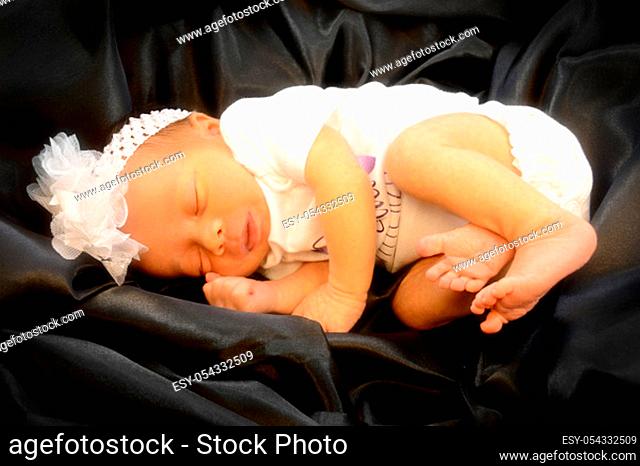 Closeup of a softly filtered focused new born baby girl who is gently drifted away in a sleepy cuteness