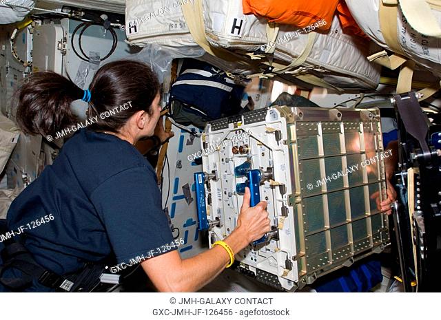 Astronaut Nicole Stott, Expedition 20 flight engineer, prepares to move hardware through a hatch on the middeck of Space Shuttle Discovery (STS-128) while...
