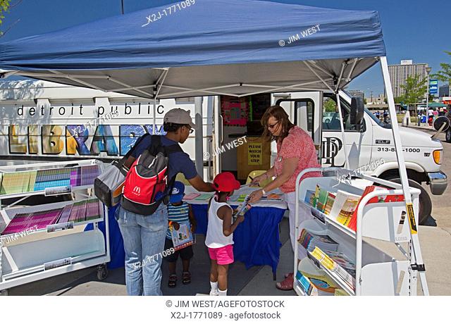 Detroit, Michigan - Laurie Stuart, a librarian for the Detroit Public Library, distributes free books to children at the library's bookmobile during a summer...