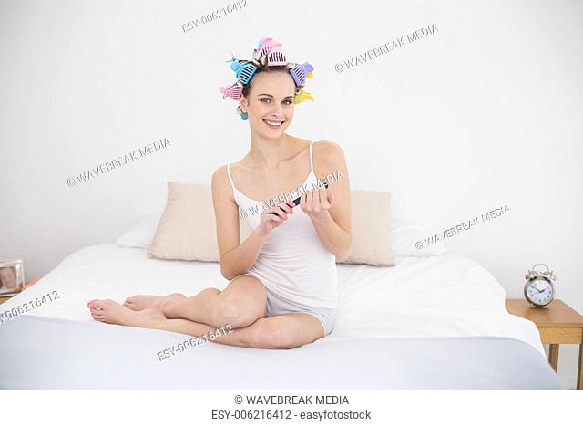 Relaxed natural brown haired woman in hair curlers filing her nails