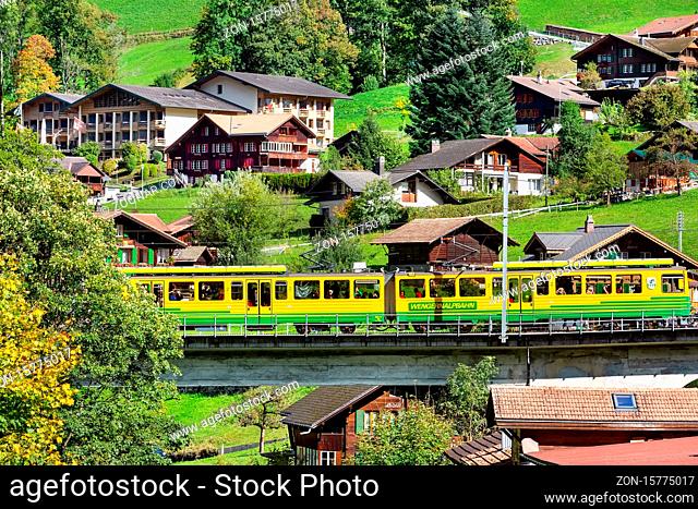 Lauterbrunnen, Switzerland - October 10, 2019: Alpine wooden houses in Swiss Alps village in autumn and Wengernalpbahn train