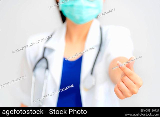 Woman doctor give a hand with fingers in the shape mini heart, wear a mask to protect Coronavirus, Show sign language as a symbol of giving love