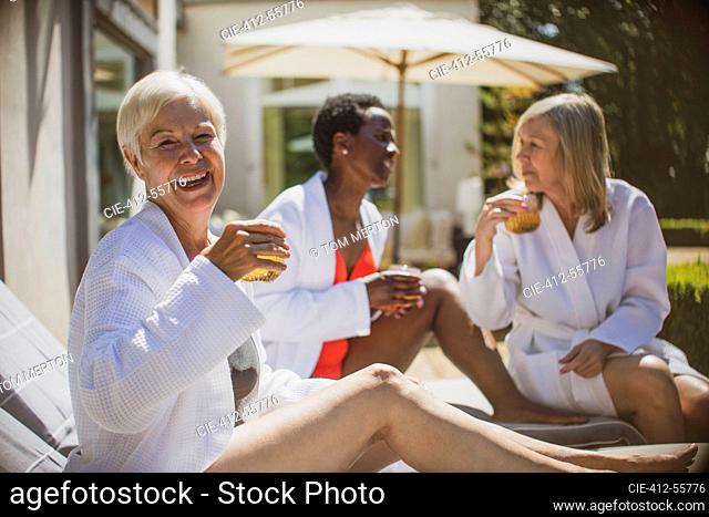 Portrait happy senior women friends relaxing on sunny hotel patio