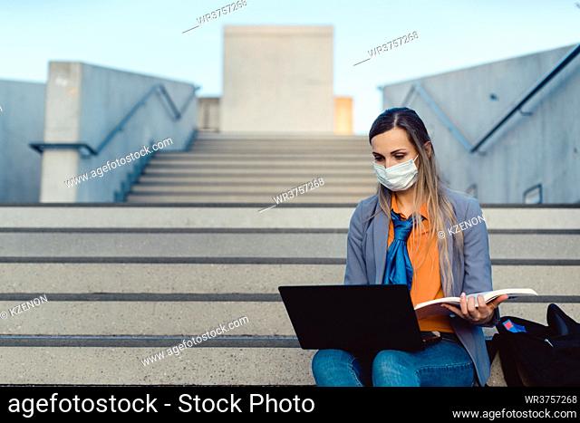 Student woman sitting on empty stairs of university campus working