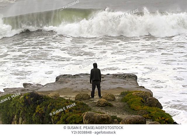 A man watches from a cliff as waves crash in Santa Cruz, California, United States. RM