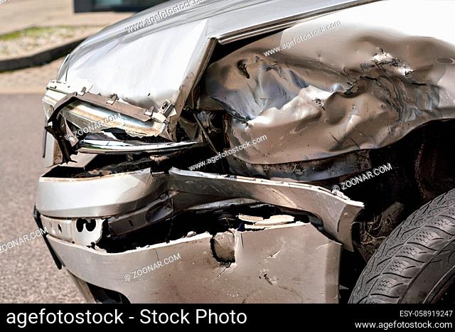 Crashed car after road accident, detail on demolished front light and metal plates