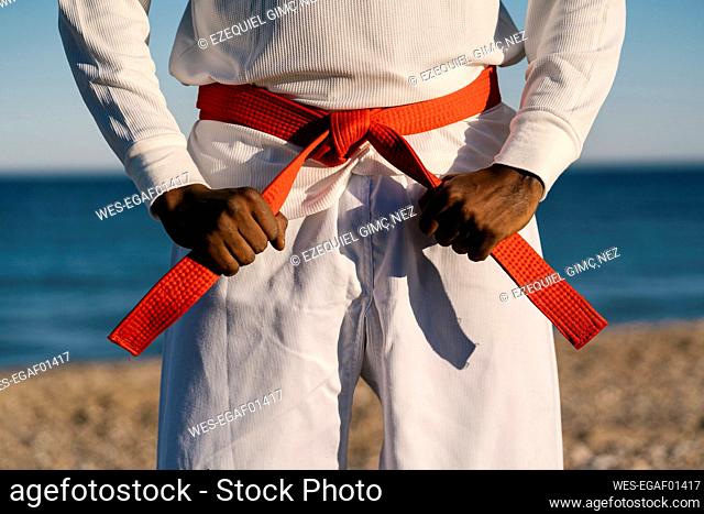 Mid section of male martial artist wearing red obi belt