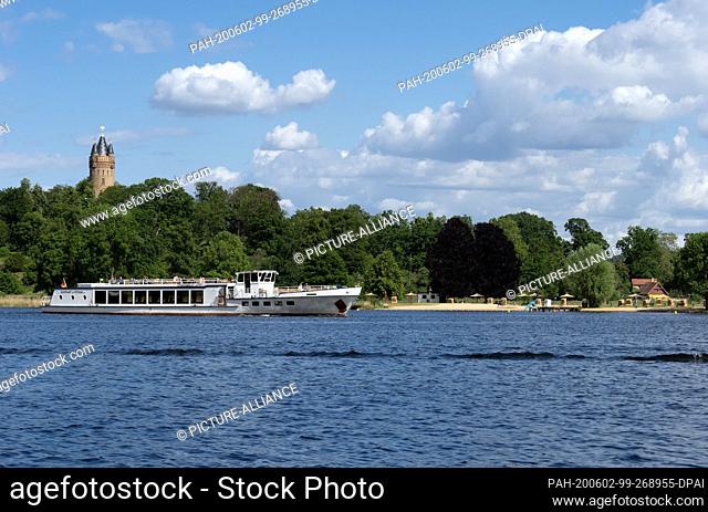 28 May 2020, Brandenburg, Potsdam: The excursion steamer ""Königswald"" sails on the Tiefen See past the Flatow Tower (l) and the lido in Park Babelsberg