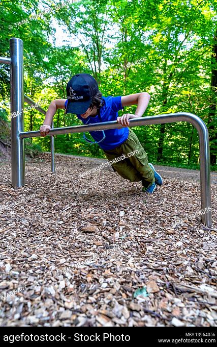 Europe, Germany, Baden-Wuerttemberg, Northern Black Forest, Bad Liebenzell, boy doing pushups on a scaffold on the fitness trail