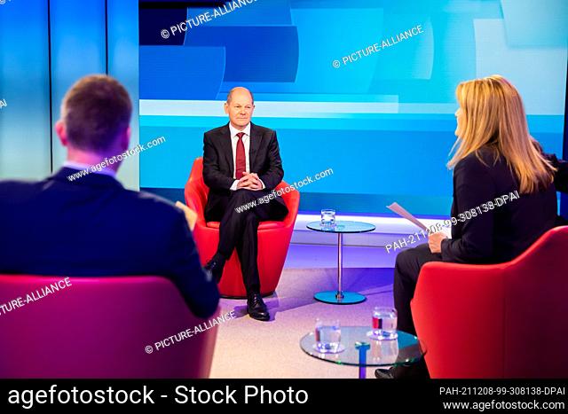 08 December 2021, Berlin: Chancellor Olaf Scholz (SPD) sits with Tina Hassel, head of the ARD capital studio, and Oliver Köhr, ARD editor-in-chief