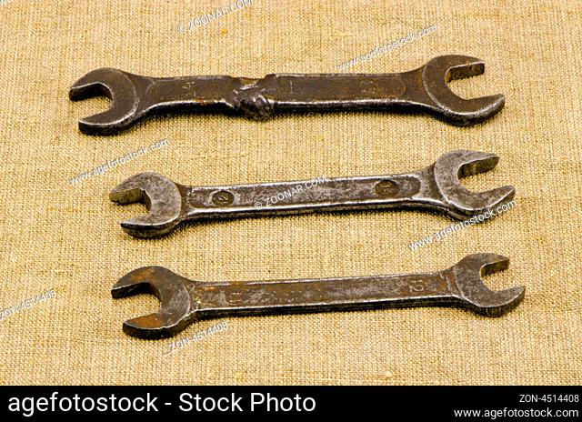 three retro different size screw spanners wrench tools on linen cloth cloth background