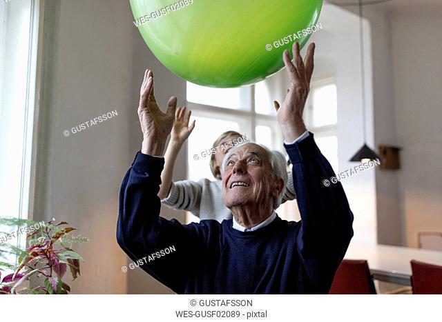 Happy grandfather and grandson playing with balloon at home
