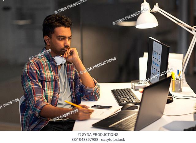 creative man with laptop working at night office
