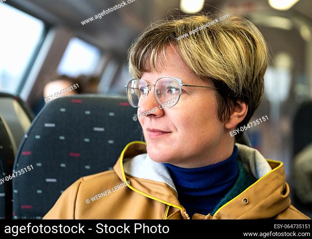 37 yo white woman with glasses, sitting on a train, Tienen, Flanders, Belgium