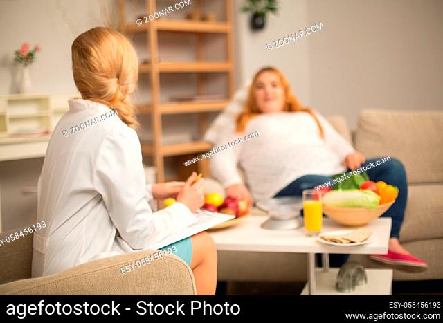 Overweight patient nd nutritionist having conversation. Patient listenting to doctor attentively