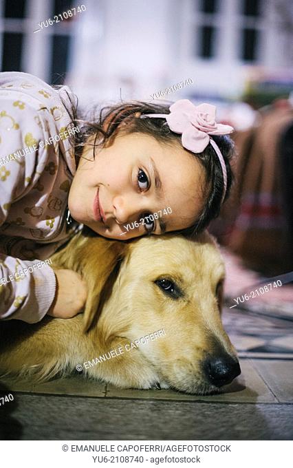 Little girl and her dog golden retriever, rests his head on the dog