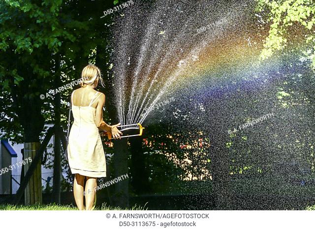 A woman waters the grass with a hose in the Hagalund Park and apartment complex, Solna suburb. Stockholm, Sweden