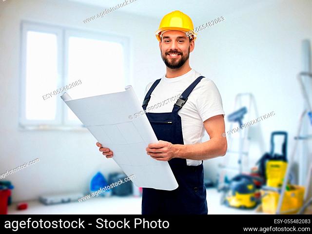 male worker or builder in helmet with blueprint