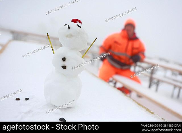 20 April 2023, Saxony-Anhalt, Schierke: A snowman stands on a snow-covered table of an outdoor restaurant on the Brocken