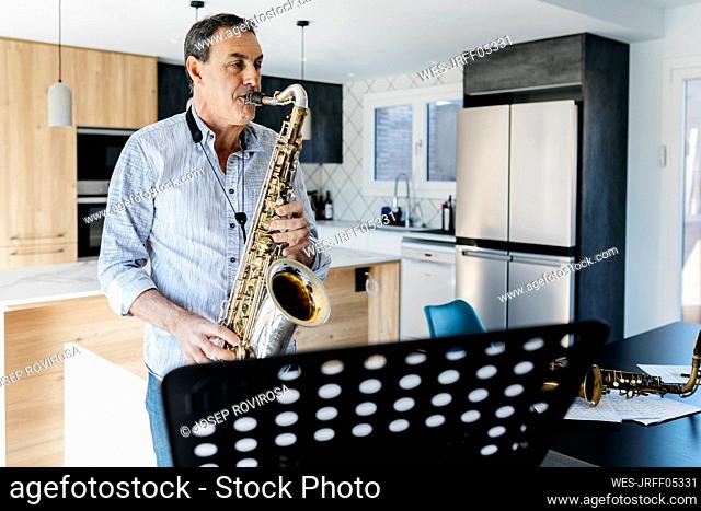 Saxophonist practicing saxophone standing in kitchen at home