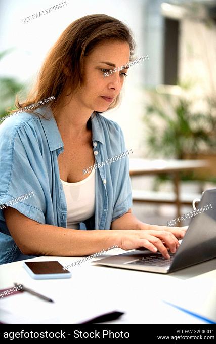 Adult woman using laptop while working on laptop at design studio