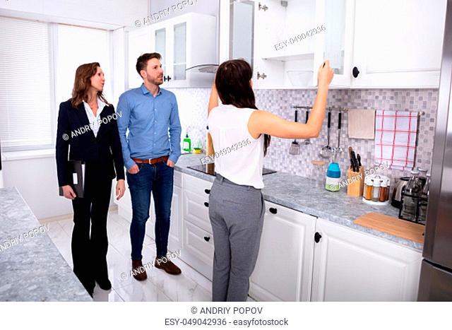 Young Woman Checking Kitchen Cabinet During Meeting With Real Estate Agent