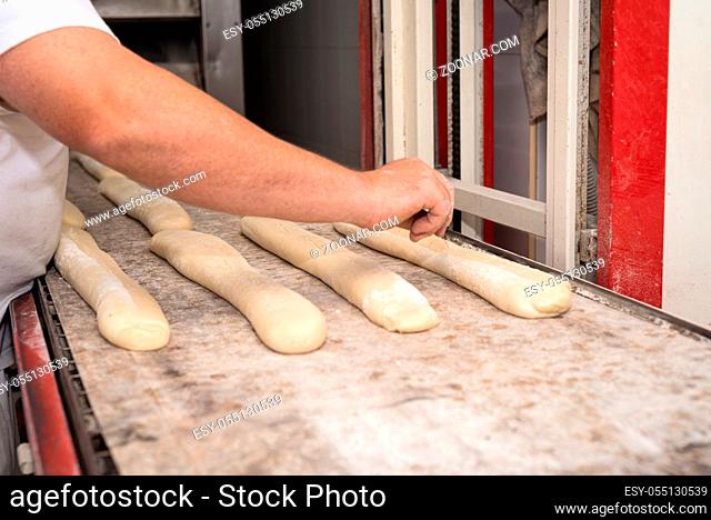 Baker preparing uncooked bread dough loaves ready to bake