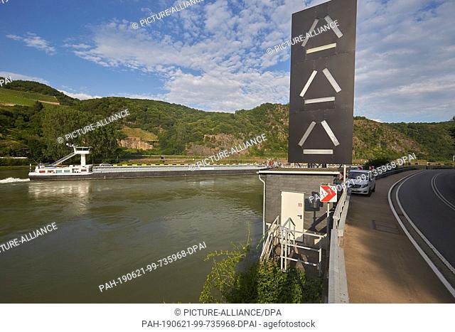 19 June 2019, Rhineland-Palatinate, St. Goar: A cargo ship passes the traffic lights at Betteck opposite the Loreley rock on the Middle Rhine
