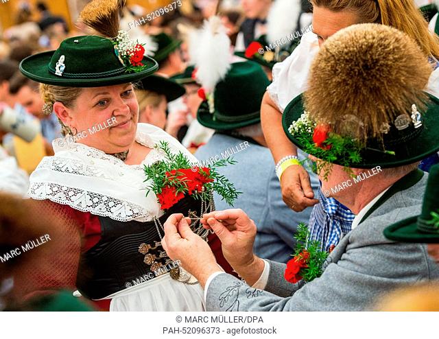 Two persons wearing traditional costumes stand in the 'Oide Wiesn' festival tent after the costume and shooting club parade at the Oktoberfest in Munich...