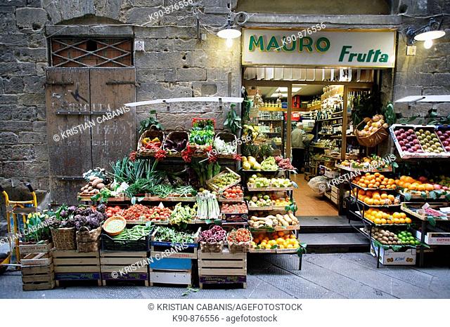 Traditional grocery store selling fruit and vegetable - and a pushcart besides - in a side street of the heart of Florence (Firenze), Tuscany, Italy