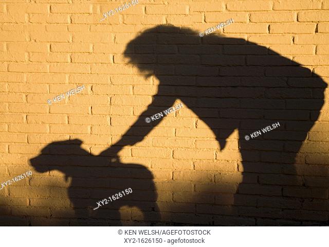 Shadow of woman and dog against brick wall