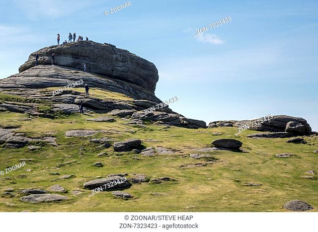 Haytor or Hay Tor rocks with tourists and visitors climbing up the granite rock on Dartmoor, Devon, England, United Kingdom