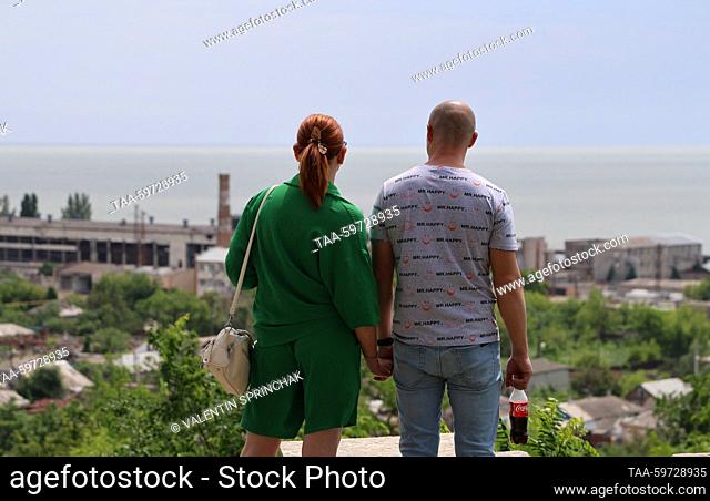 RUSSIA, DONETSK PEOPLE'S REPUBLIC - JUNE 10, 2023: People hold hands as they look at the Sea of Azov in Mariupol. Valentin Sprinchak/TASS