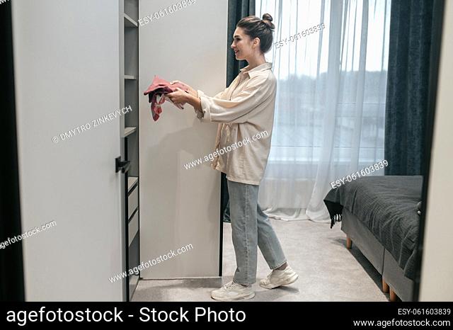 Choosing clothes. A woman standing near the wardrobe in the bedroom
