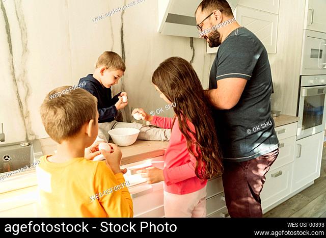 Man with children preparing breakfast in kitchen