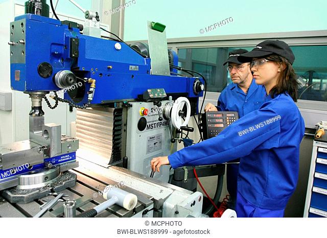 female apprentice working with machines, training supervisor watching
