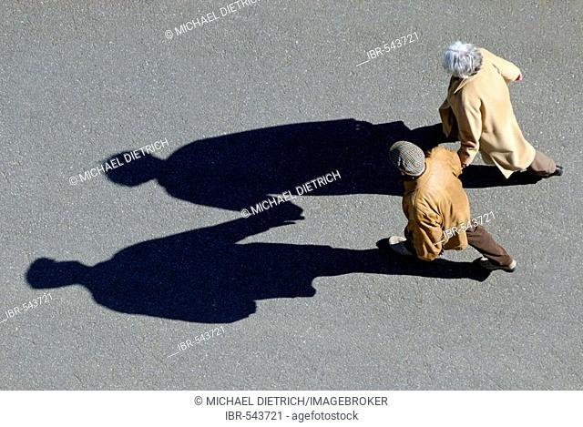 Senior couple walking hand-in-hand, bird's eye view with shadow