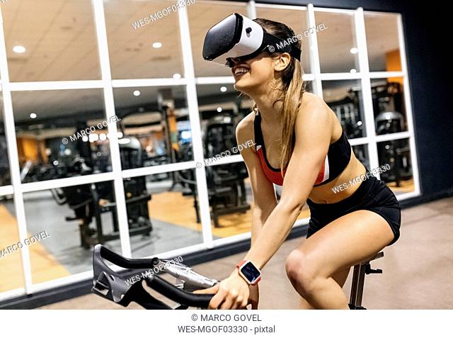 Woman with VR glasses on spinning bike in the gym
